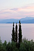 CORFU, GREECE - THE KASSIOPIA ESTATE. VIEW LOOKING OUT TO SEA WITH CYPRESS TREES AND THE ALBANIAN MOUNTAINS IN THE DISTANCE
