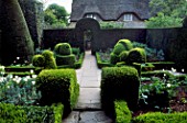 PATH RUN BETWEEN BEDS EDGED WITH CLIPPED BOX AND TOPIARY SHAPES AND THROUGH ARCH IN YEW HEDGE. HIDCOTE MANOR GARDEN  GLOUCESTERSHIRE