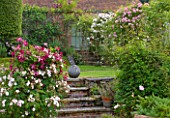 POULTON HOUSE GARDEN, WILTSHIRE: THE WALLED ROSE GARDEN - BRICK STEPS LEADING UP TO LAWN WITH ROSES - ROSES ON PERGOLAS - COUNTRY GARDEN, SUMMER. CLIMBING ROSES