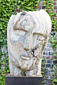 POULTON HOUSE GARDEN, WILTSHIRE: STONE SCULPTURE OF FACE IN WALLED GARDEN - MARBLE SCULPTURE - HERACLITUS - BY EMILY YOUNG