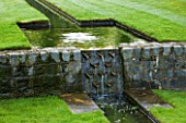 POULTON HOUSE GARDEN, WILTSHIRE: WATER FEATURE. DETAIL OF A DESCENDING FLIGHT OF RILLS SET INTO SUNKEN LAWN, WITH WATER CASCADE