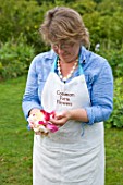 COMMON FARM FLOWERS, SOMERSET, SUMMER: FLOWER FARMER AND FLORIST GEORGIE NEWBERRY IN THE GARDEN WITH ROSE PETALS FOR CONFETTI - FLOWER, FLOWERS, POSIE, HANDS, NATURAL