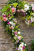 COMMON FARM FLOWERS, SOMERSET, SUMMER: FLORAL WREATH MADE FROM FRESH FLOWERS PICKED FROM THE GARDEN - ROSES, SWEET WILLIAM, GOLDEN HOP. GREEN, LEAVES, GARLAND, HEART