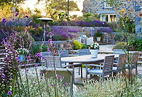 LE_HAUT_GUERNSEY_VIEW_ACROSS_PATIO_WITH_LAVENDER_VERBENA_BONARIENSIS_WOODEN_TABLE_AND_CHAIRS__OUTDOO