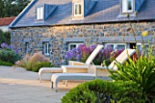 LE HAUT, GUERNSEY: BORDER BY SWIMMING POOL WITH DECK CHAIRS, STIPA TENUISSIMA AND CAMPANULA