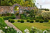 LE HAUT, GUERNSEY: THE FRONT GARDEN WITH LAWN, BOX BALLS AND STONE WALL WITH ARCHWAY