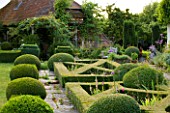 WOOLSTONE MILL HOUSE, OXFORDSHIRE: FORMAL PARTERRE IN FRONT OF HOUSE WITH STONE PATH, BOX BALLS AMD PERENNIALS. JULY.FORMAL STYLE COUNTRY GARDEN.