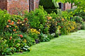 CHENIES MANOR, BUCKINGHAMSHIRE: BORDER BESIDE THE MANOR HOUSE WITH LAWN, DAHLIAS, HELENIUMS, RUDBECKIAS, CROCOSMIA AND TRADESCANTIA - HERBACEOUS, LATE SUMMER, COUNTRY, CLASSIC