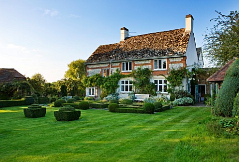 WOOLSTONE_MILL_HOUSE_OXFORDSHIRE_THE_HOUSE_VIEWED_FROM_THE_LAWN_WITH_BOX_FONDANTS_AND_FORMAL_PARTERR