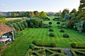 WOOLSTONE MILL HOUSE, OXFORDSHIRE: VIEW FROM FORMAL PARTERRE ACROSS LAWN WITH YEW HEDGES AND BOX FONDANTS. TOPIARY. VIEWS TO COUNTRYSIDE BEYOND. STRUCTURE, SHAPE, FORM, GREEN