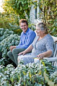 WOOLSTONE MILL HOUSE, OXFORDSHIRE: OWNER JUSTIN SPINK WITH MOTHER PENNY RELAXING ON A CHAIR IN FRONT OF THE HOUSE