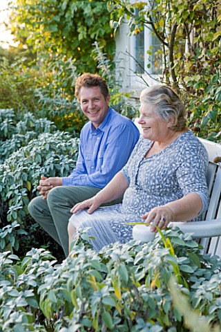 WOOLSTONE_MILL_HOUSE_OXFORDSHIRE_OWNER_JUSTIN_SPINK_WITH_MOTHER_PENNY_RELAXING_ON_A_CHAIR_IN_FRONT_O