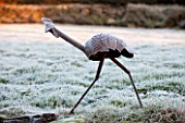 SEDGWICK PARK, WEST SUSSEX. RUSTED METAL BIRD SCULPTURE ON FROSTY LAWN. WINTER, JANUARY, GARDEN, FROST.