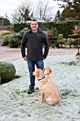 SEDGWICK PARK, WEST SUSSEX. GARDENER KEVIN TOMS WITH LABRADORS IN THE GARDEN. WINTER, FROST, JANUARY.