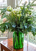 BUTTER WAKEFIELD HOUSE, LONDON. CHRISTMAS: SITTING ROOM - A GIANT GREEN GLASS PICKLE JAR WITH SEASONAL FOLIAGE AND WHITE AMARYLLIS FLOWERS