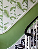 BUTTER WAKEFIELD HOUSE, LONDON. THE HALLWAY AT CHRISTMAS: DETAIL OF PALM FROND WALLPAPER, PEA GREEN PAINT AND BOLD STRIPED STAIR CARPET
