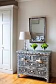BUTTER WAKEFIELD HOUSE, LONDON. ZOES BEDROOM AT CHRISTMAS: MOTHER OF PEARL INLAY CHEST OF DRAWERS WITH ANTIQUE BLACK & WHITE MIRROR AND GLASS LAMP