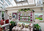 BUTTER WAKEFIELD HOUSE, LONDON. THE GARDEN ROOM AT CHRISTMAS. GLASS CONSERVATORY JUST OFF THE KITCHEN WITH SOFA AND BUTTERS CHINA PLATES DISPLAYED ON PLATE RACK