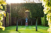 EAST RUSTON OLD VICARAGE GARDEN, NORFOLK: CLIPPED HORNBEAM ON STILTS WITH VIEW TO URN ON PEDESTAL  - VISTA, VIEW, FOCAL POINT