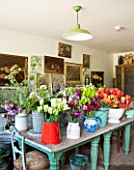 THE LAND GARDENERS, WARDINGTON MANOR, OXFORDSHIRE: THE FLOWER ARRANGING ROOM IN SPRING FILLED WITH FLOWERS IN CONTAINERS READY FOR ARRANGING, CUTTING, CUT FLOWERS