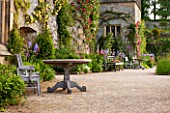 HADDON HALL, DERBYSHIRE: TERRACE BESIDE HALL WITH WOODEN TABLE AND CHAIRS, ROSES AND IRISES