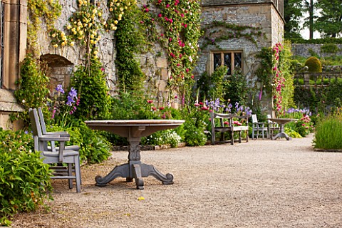 HADDON_HALL_DERBYSHIRE_TERRACE_BESIDE_HALL_WITH_WOODEN_TABLE_AND_CHAIRS_ROSES_AND_IRISES