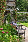 HADDON HALL, DERBYSHIRE: TERRACE BESIDE HALL WITH WOODEN BENCH, TABLE AND CHAIRS, ROSES, POPPIES AND IRISES