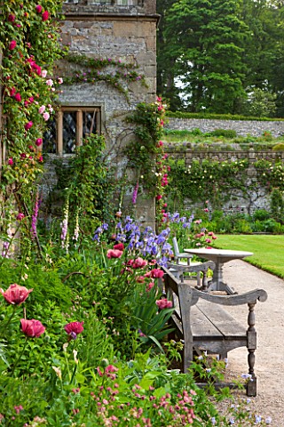 HADDON_HALL_DERBYSHIRE_TERRACE_BESIDE_HALL_WITH_WOODEN_BENCH_TABLE_AND_CHAIRS_ROSES_POPPIES_AND_IRIS