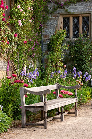 HADDON_HALL_DERBYSHIRE_TERRACE_BESIDE_HALL_WITH_WOODEN_BENCH_ROSES_POPPIES_AND_IRISES