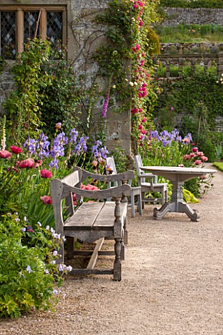 HADDON_HALL_DERBYSHIRE_TERRACE_BESIDE_HALL_WITH_WOODEN_BENCH_TABLE_AND_CHAIRS_ROSES_POPPIES_AND_IRIS