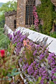 HADDON HALL, DERBYSHIRE: WALL WITH FLOWERS AND VIEW TO THE CHAPEL