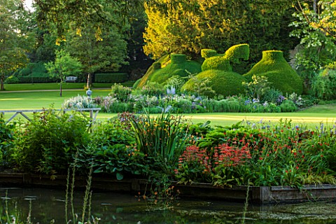ABLINGTON_MANOR__GLOUCESTERSHIRE_VIEW_ACROSS_COLN_RIVER_TO_ISLAND_BED_AND_CLIPPED_YEW_TOPIARY_REFLEC