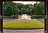 GREAT FOSTERS, SURREY: VIEW THROUGH THE FRONT DOOR OF THE HOTEL WITH DRIVE AND CLIPPED TOPIARY SHAPES - YEW, VIEWPOINT, FRAME, FRANING, JUNE, COUNTRY GARDEN, PATTERN