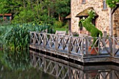 OLD NETLEY MILL, SHERE, SURREY: WOODEN DECKED TERRACE BESIDE THE MILL AND LAKE WITH TOPIARY HORSE IN CONTAINER , PATIO, SUMMER, JUNE, GARDEN