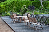 OLD NETLEY MILL, SHERE, SURREY: DECKED WOODEN TERRACE WITH WOODEN TABLE AND CHAIRS - TOPIARY HORSE IN CONTAINER. GARDEN, SUMMER