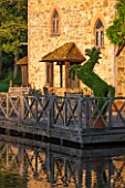 OLD NETLEY MILL, SHERE, SURREY: DECKED TERRACE IN FRONT OF THE MILL WITH TOPIARY HORSE IN CONTAINER
