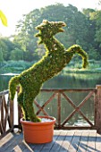 OLD NETLEY MILL, SHERE, SURREY: DECKED TERRACE WITH TOPIARY HORSE IN CONTAINER. JUNE, SUMMER