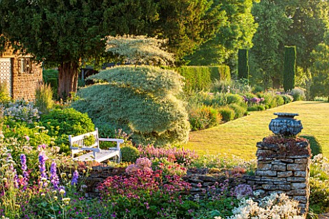 PETTIFERS_GARDEN_OXFORDSHIRE_EARLY_MORNING_VIEW_FROM_THE_BACK_OF_THE_HOUSE_WITH_LAWN_WOODEN_BENCH__S