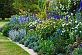 BROUGHTON CASTLE, OXFORDSHIRE: BORDER BESIDE THE WALLED GARDEN WITH DELPHINIUMS, PHLOMIS RUSSELIANA AND STCAHYS BYZANTINA  - SUMMER, JUNE, FLOWERS