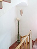 CIUTADELLA MENORCA, SPAIN: EVELYNE MANDEL HOUSE - WOODEN STAIRCASE WITH WHITE WALLS AND TERRACOTTA TILES ON FLOOR - GREEN ANTIQUE PARISIAN HAT STAND