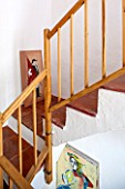 CIUTADELLA MENORCA, SPAIN: EVELYNE MANDEL HOUSE - WOODEN STAIRCASE WITH WHITE WALLS AND TERRACOTTA TILES ON FLOOR - MENORCAN PAINTINGS