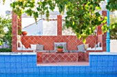 JONATHAN BAILLIE GARDEN, ALAIOR, MENORCA: TERRACOTTA TILED SEATING AND DINING AREA BEHIND SWIMMING POOL.  FOOD, DINING, ENTERTAINING AREA, OUTDOOR LIFESTYLE