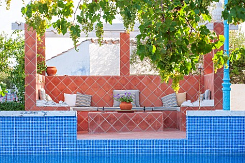 JONATHAN_BAILLIE_GARDEN_ALAIOR_MENORCA_TERRACOTTA_TILED_SEATING_AND_DINING_AREA_BEHIND_SWIMMING_POOL