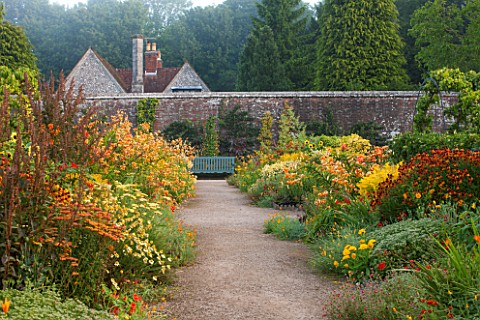 WEST_DEAN_GARDENS_WEST_SUSSEX_LATE_SUMMER_BORDERS_IN_THE_WALLED_VEGETABLE_GARDEN__PATH_TO_SEAT__BENC