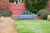 LAMPORT HALL, NORTHAMPTONSHIRE: THE WALLED CUTTING GARDEN / KITCHEN GARDEN: BLUE BENCH BESIDE GRASS PATH WITH WALL AND GATE BEHIND. SUMMER
