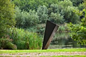 GREAT FOSTERS. SURREY:  THE JUGGERNAUT OF NAUGHT - SCULPTURE IN MILD WELDED STEEL BY RICHARD TRUPP BESIDE THE LAKE - ART, CONTEMPORARY