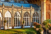 SEZINCOTE, GLOUCESTERSHIRE: THE MAGNIFICENT CURVING ORANGERY WITH CONTAINERS OF FUCHSIAS OUTSIDE IN MORNING LIGHT