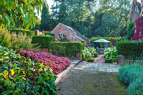 SURREY_GARDEN_DESIGNED_BY_ANTHONY_PAUL_VIEW_ALONG_PATH_WITH_SEDUMS_TO_FORMAL_GARDEN_WITH_BEDS_PLANTE