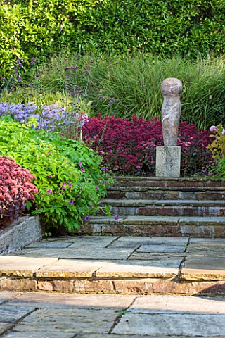 SURREY_GARDEN_DESIGNED_BY_ANTHONY_PAUL_PATH_WITH_SEDUMS_AND_GRASSES_TO_FOCAL_POINT_OF_POLISHED_STONE