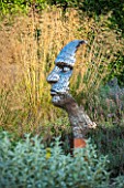 SURREY GARDEN DESIGNED BY ANTHONY PAUL: FOCAL POINT - PIXELATED STYLE STEEL HEAD BY RICK KIRBY WITH STIPA GIGANTEA BEHIND - SUMMER, SEPTEMBER, COUNTRY GARDEN
